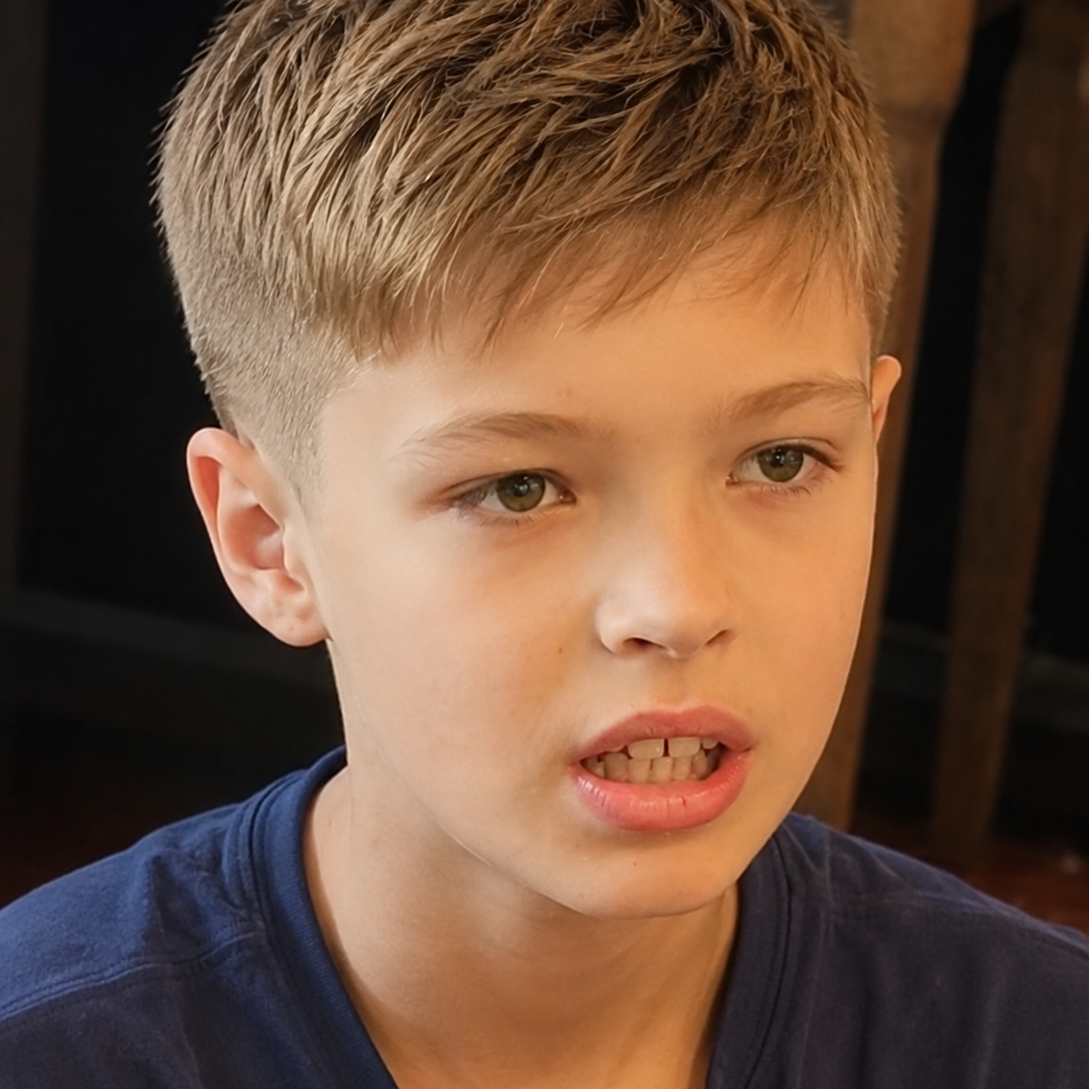 Haircuts for young girls with ASD, Pathological demand avoidance in London Young boy with short hair, wearing a blue shirt, looking intently while speaking.